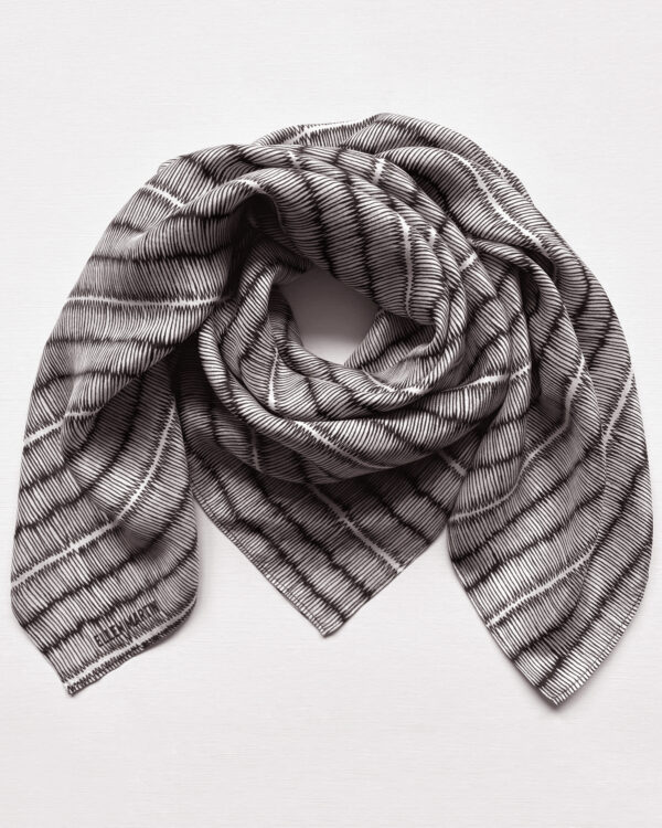 Large square silk scarf with intricate repeat pattern in black and off-white.