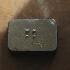 silver bauble studs flat lay on a vintage metal tin on a wooden surface