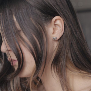 close up of a heart shaped stud on a womans ear