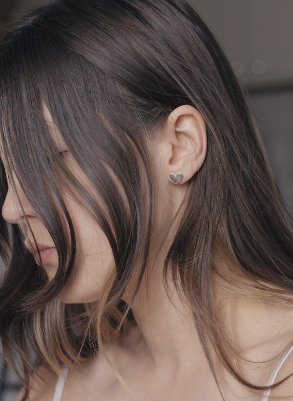 close up of a heart shaped stud on a womans ear