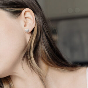 closeup of a heart shaped earring on a womans ear
