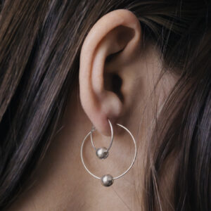 very close up earrings in a womans ear, showing two hoops together