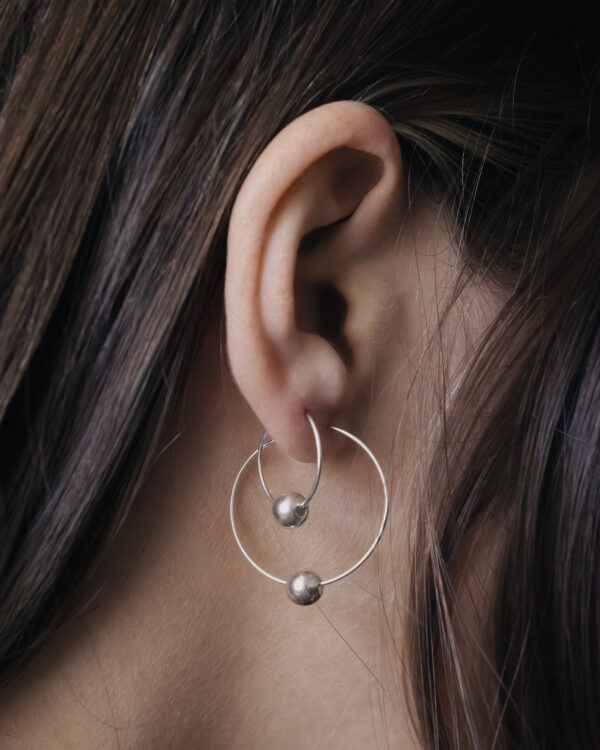 very close up earrings in a womans ear, showing two hoops together