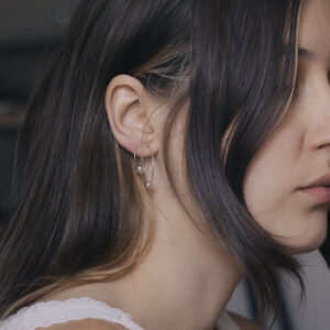 close up side view of a woman with two silver bauble hoops in one ear