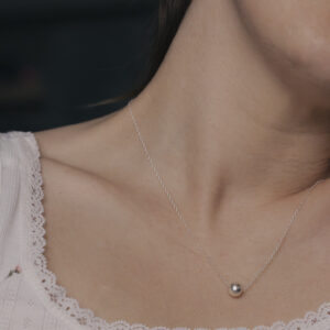 bauble necklace on a womans neck, she is leaning out of frame