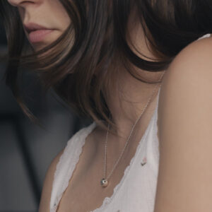 side view of a silver necklace on a woman in a white vest