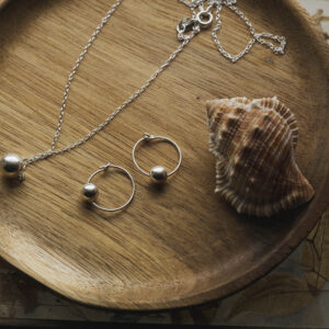 bauble hoops and necklace on a wooden tray with a shell also on the tray