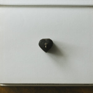single gold stud atop a vintage heart shaped jewellery box