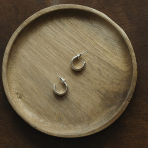 silver hoops displayed on a small wooden round tray.