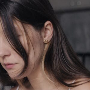 close up of a woman wearing gold heart shaped studs