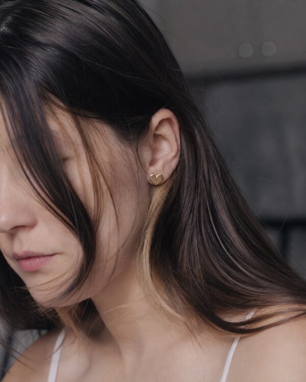 close up of a woman wearing gold heart shaped studs
