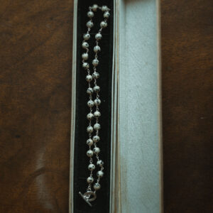 beaded necklace displayed in a vintage jewellery box on a wooden surface
