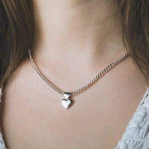 close up of a silver heart necklace on womans neck